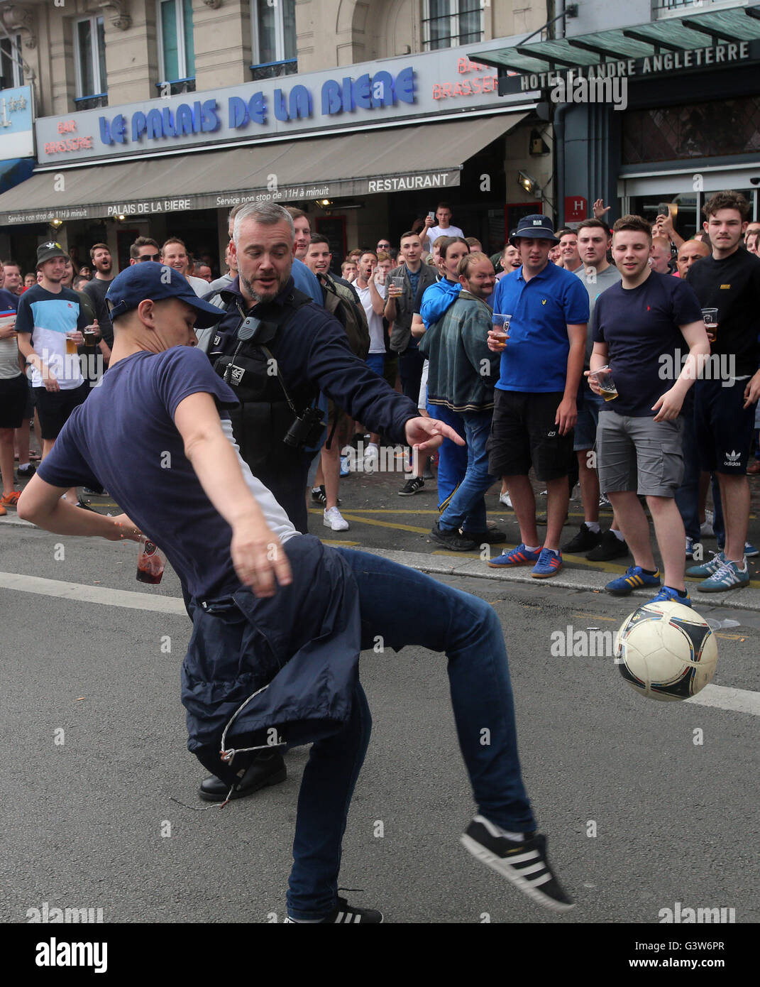 Ein Polizist bewegt Fans spielen Fußball abseits der Straße in Lille, Frankreich, wie frische Auseinandersetzungen haben zwischen England-Fans und russische Hooligans bei der Euro 2016 stattfinden. Stockfoto
