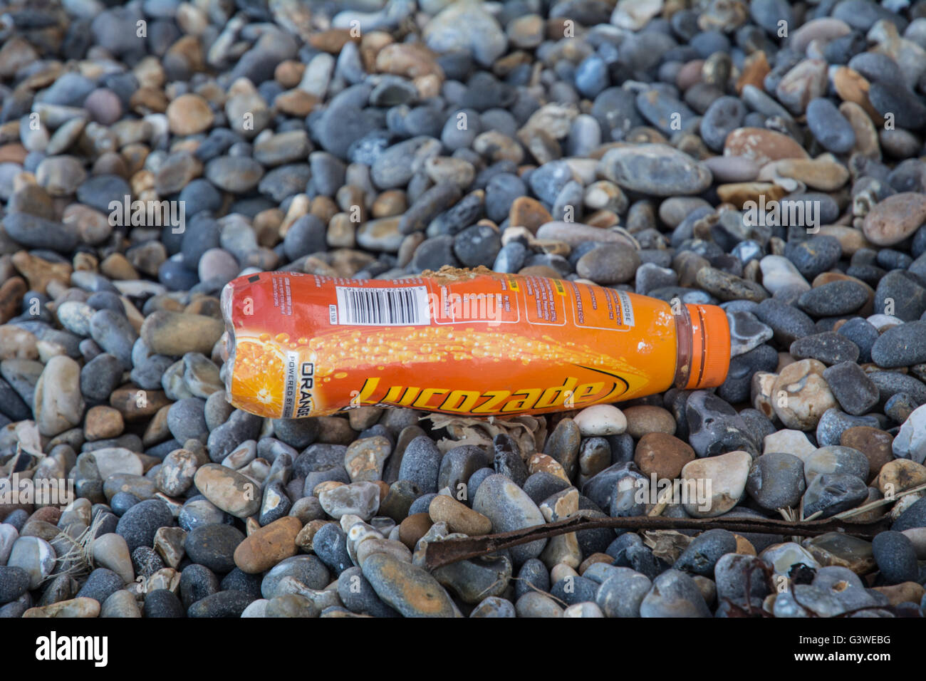 Eine Lucozade Flasche auf dem Boden an einem steinigen Strand in Norfolk. Stockfoto