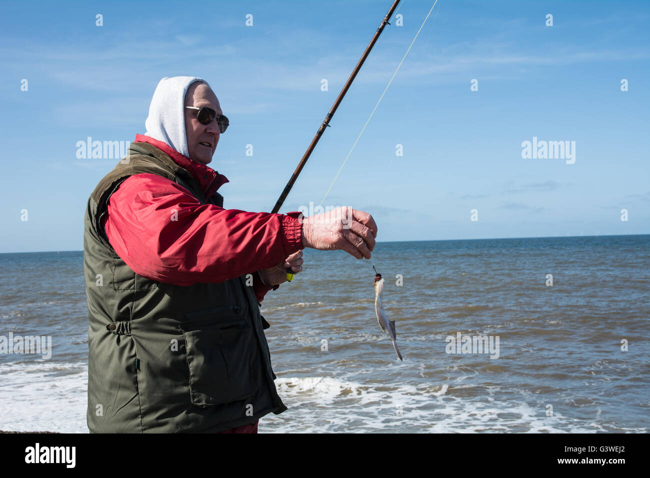 Ein Mann Meeresangeln an der Küste von Norfolk seinen Fang zu zeigen. Stockfoto