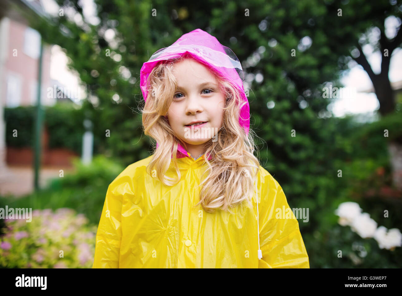 Outdoor-Foto von kleinen blonden Mädchen in gelben Regenmantel Stockfoto