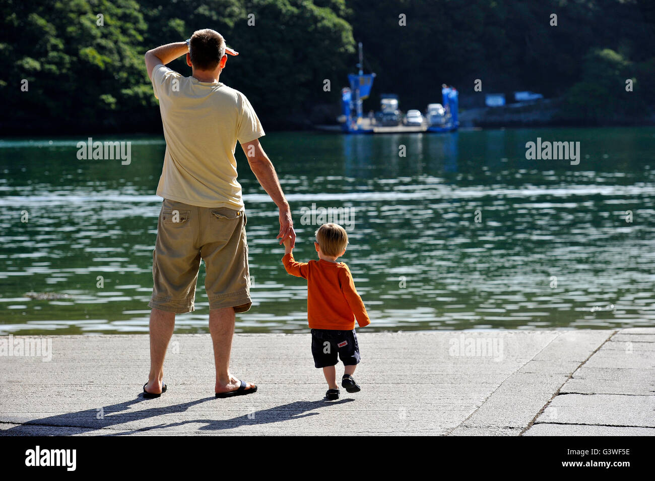 Vater und Sohn Hand in Hand warten am Kai König Harry Ferry über St.Just in Roseland Halbinsel Stockfoto