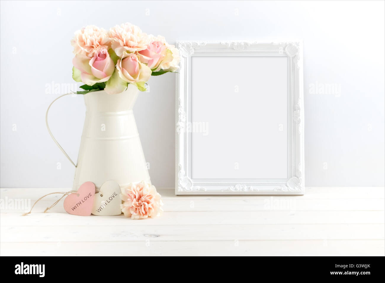 Mock-up Foto von Sahnekännchen Blumen neben einem weißen verzierten Rahmen gestaltet. Legen Sie Ihr Angebot in den Rahmen. Stockfoto