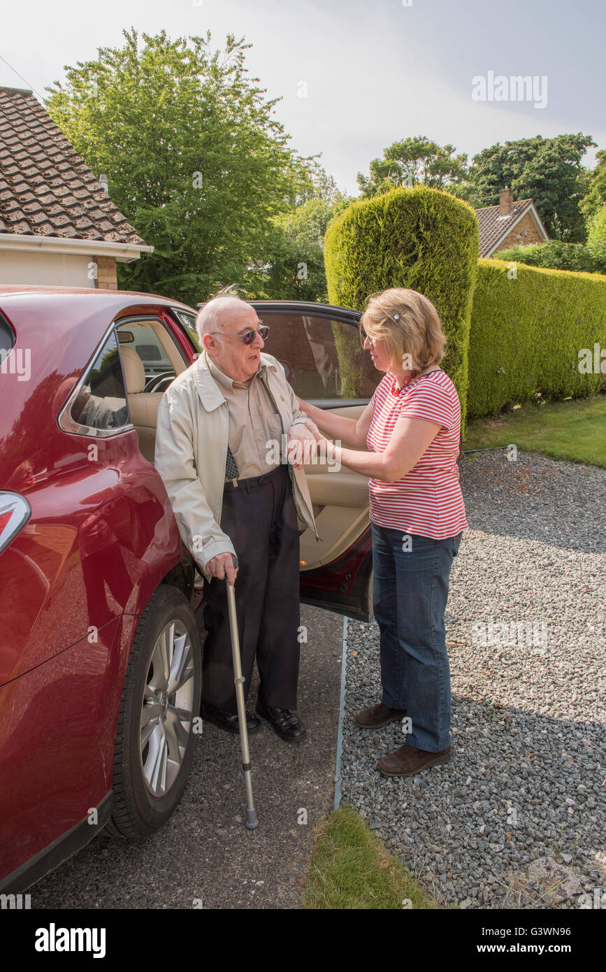 Der Mensch in seinen Neunzigern Hause motor mit dem Auto anreisen, nach möglicherweise ein Krankenhaus oder Ärzte Termin mit Tochter oder Betreuer. Stockfoto