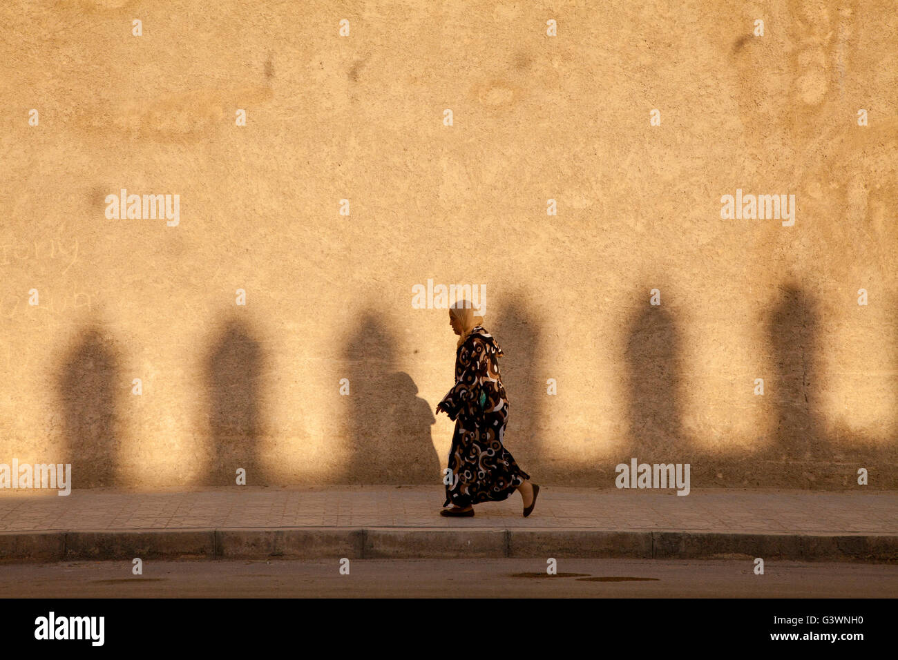 Eine Frau geht mit Stadtmauern bei Sonnenuntergang in Fès (Fes Fas) Stadt, UNESCO Weltkulturerbe in Marokko, Afrika Stockfoto