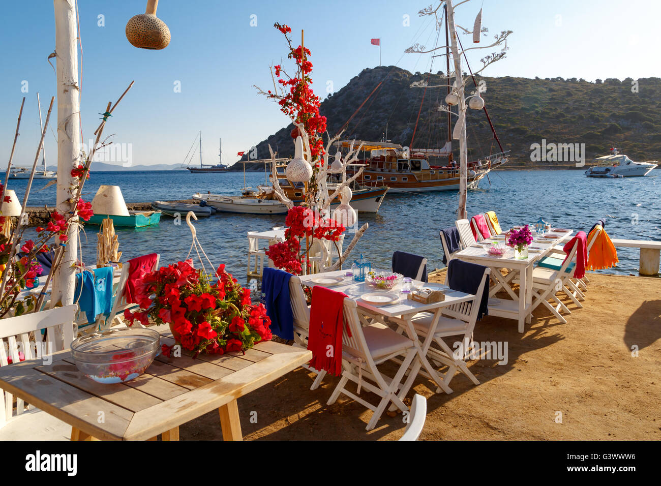 MUGLA, Türkei - 28. Mai 2016: Blick von Restaurant mit weißen Tischen und Stühlen Gumusluk Strand entlang. Stockfoto