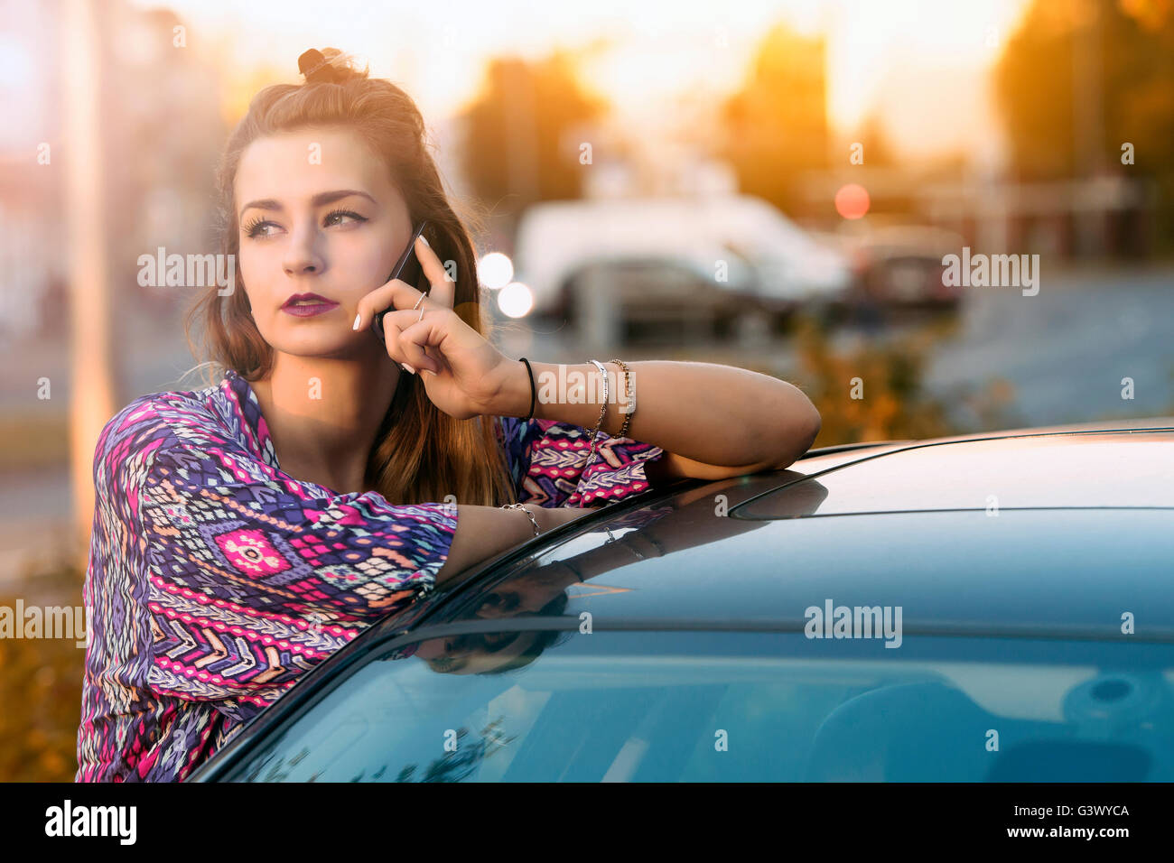 Brünette Frau ein Auto gelehnt und am Telefon sprechen Stockfoto