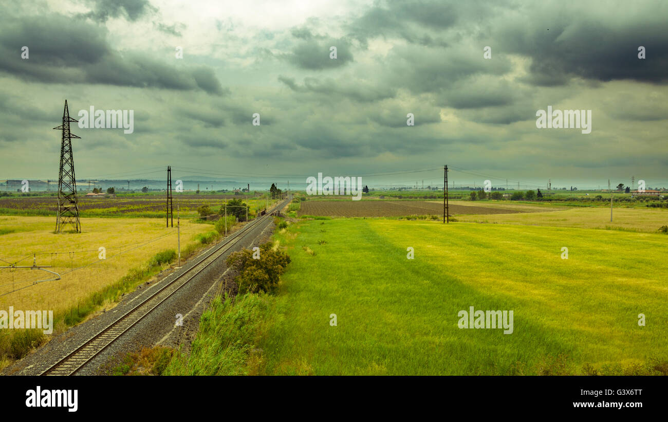 Eine horizontale Aufnahme von Eisenbahnschienen an einem bewölkten Tag bis zum Horizont erweitern Stockfoto