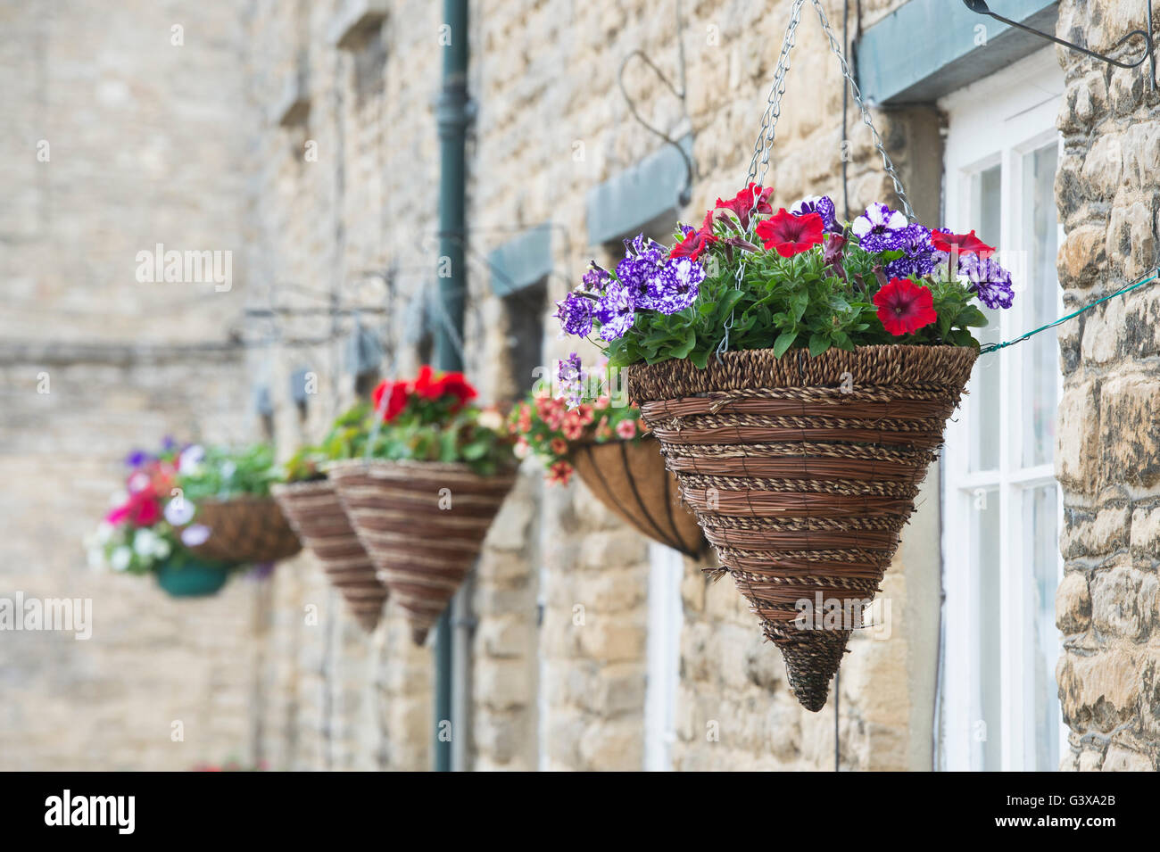 Hängenden Körben vor Steinbauten. Bampton, Oxfordshire, England Stockfoto