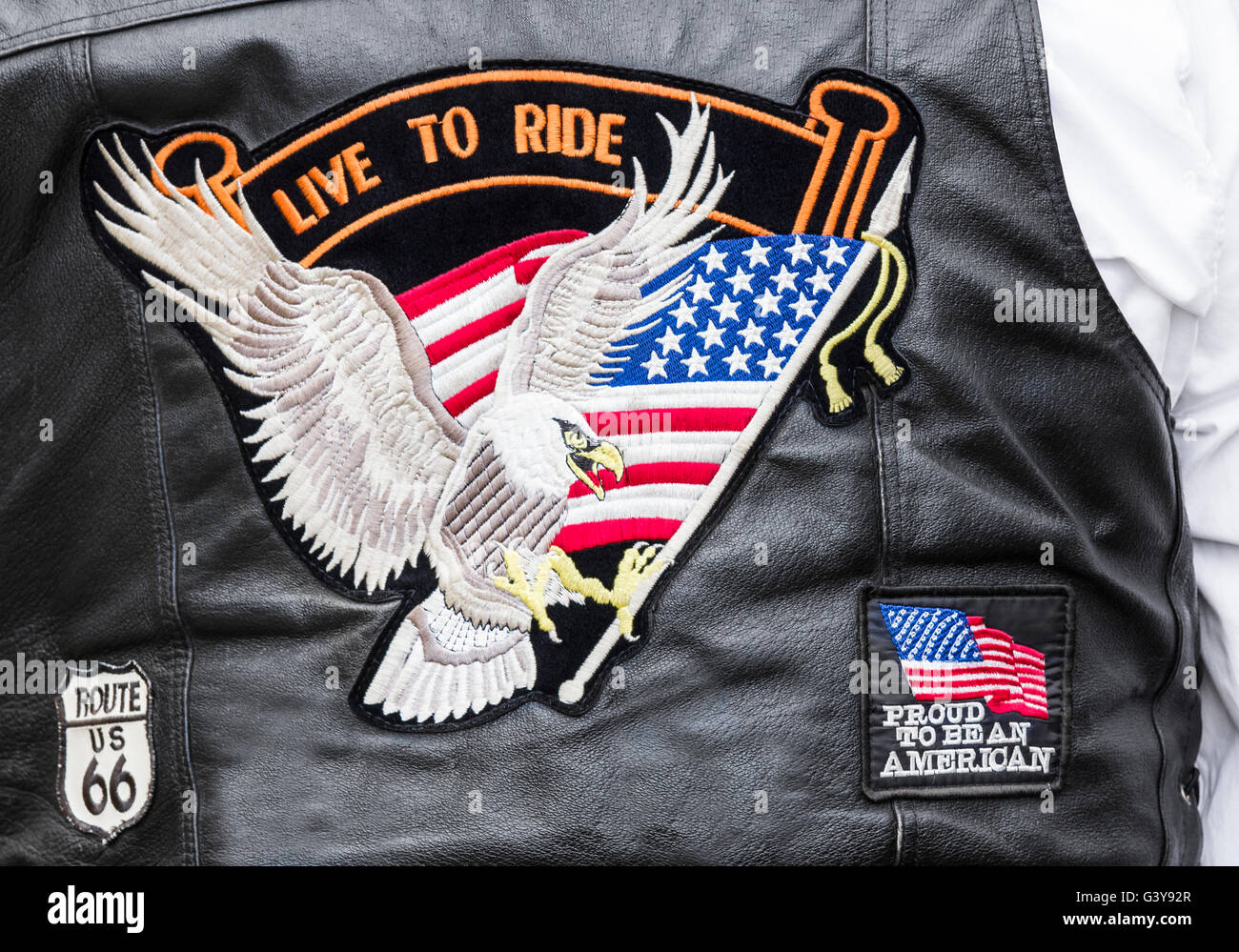Biker tragen "Live zu fahren",'stolz, Amerikaner zu sein' und 'Route 66' Abzeichen auf Rückseite Lederjacke. Stockfoto