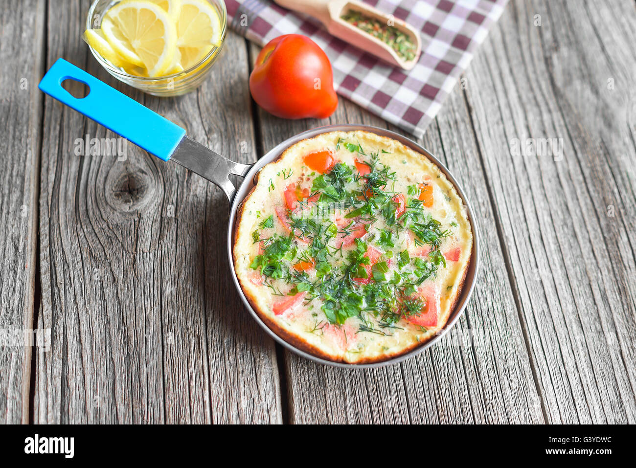 Omelette mit Gemüse in einer Pfanne auf einem Holztisch. Stockfoto