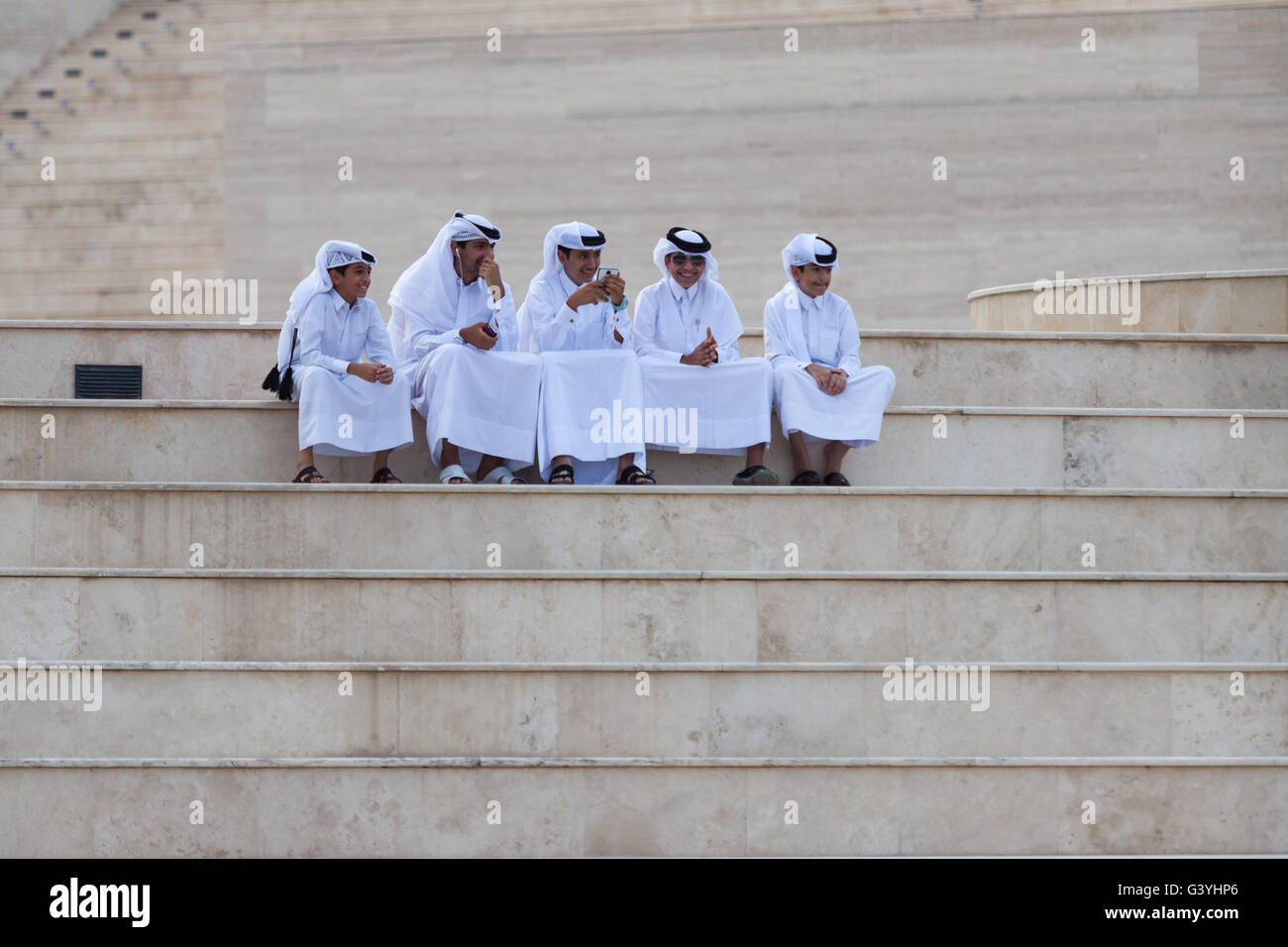 Katar Jungs in traditioneller Kleidung, sitzen im Amphitheater bei Katara Cultural Village Stockfoto