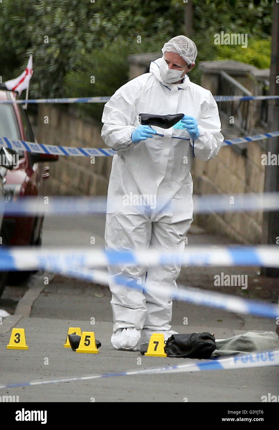 Ein Forensik-Offizier schaut ein Damenschuh am Tatort in Birstall, West Yorkshire, nach dem Tod von Labour MP Jo Cox, der starb, nachdem er erschossen und erstochen in der Straße vor ihrem Wahlkreis Beratung Chirurgie. Stockfoto