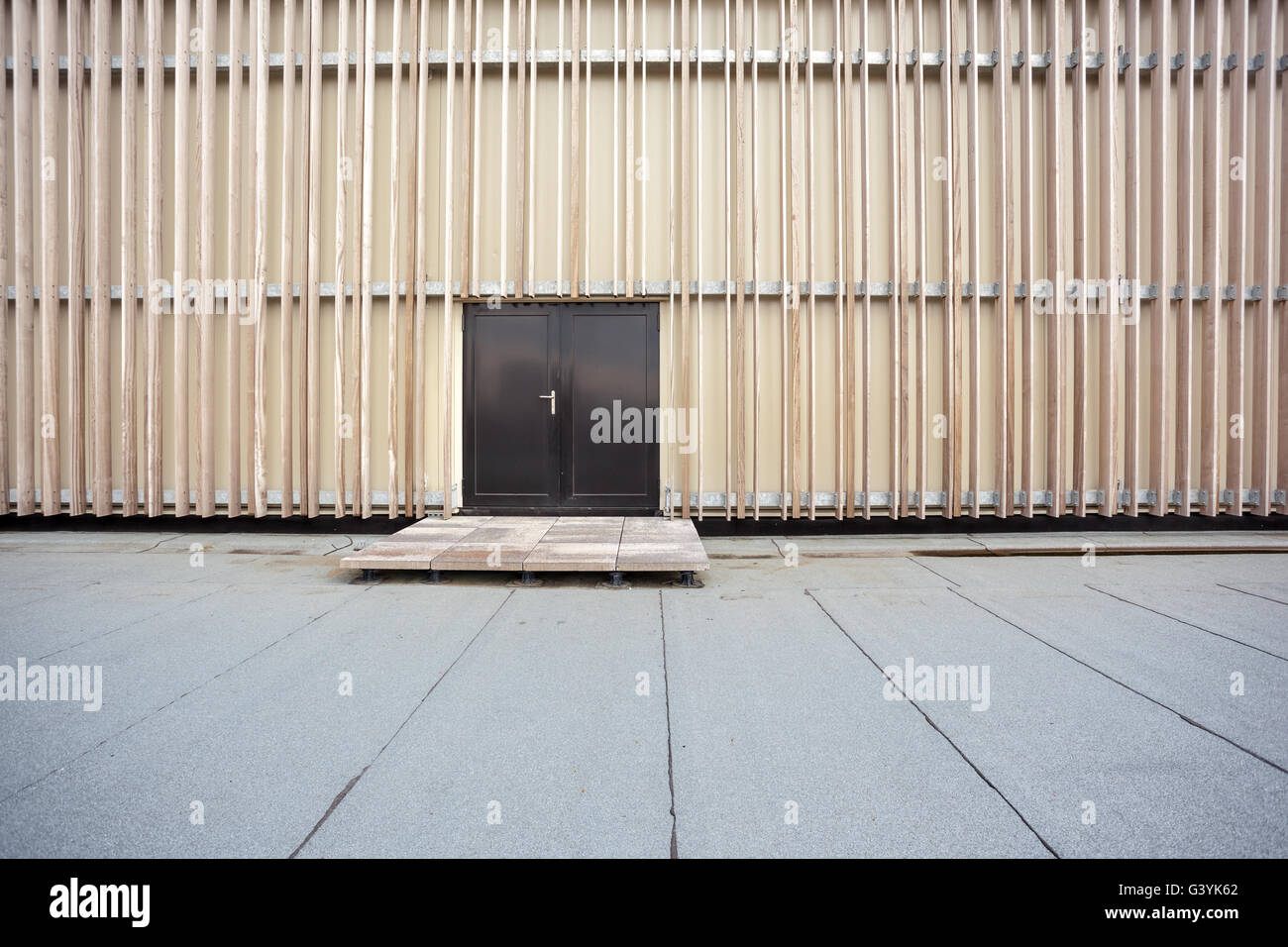 Die Wand ist gesäumt von unlackierte Holz und eine schwarze Tür Stockfoto