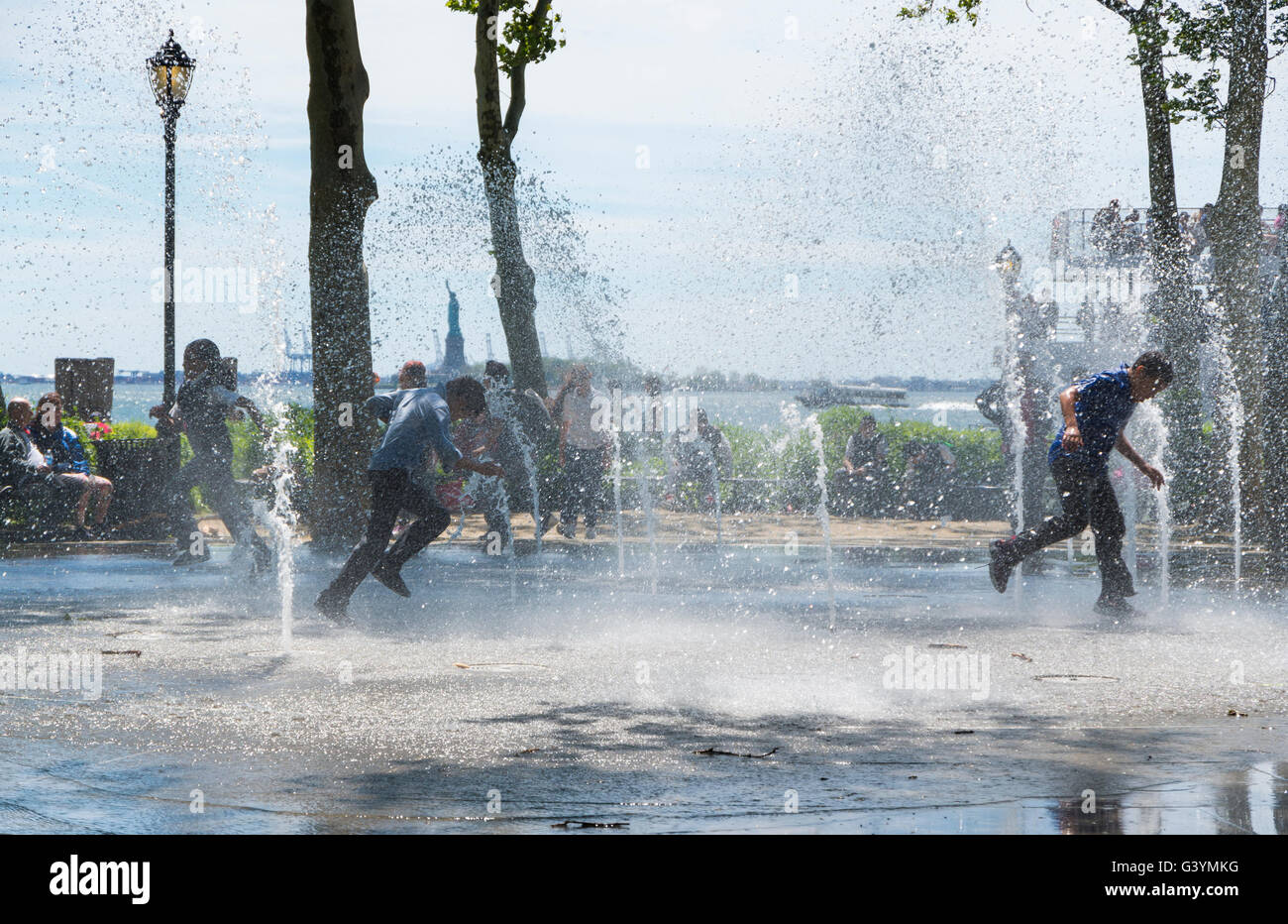 Jungs im Teenageralter läuft durch einen öffentlichen Brunnen und Flickschusterei in Battery Park, New York im Sommer kühl zu halten. Stockfoto