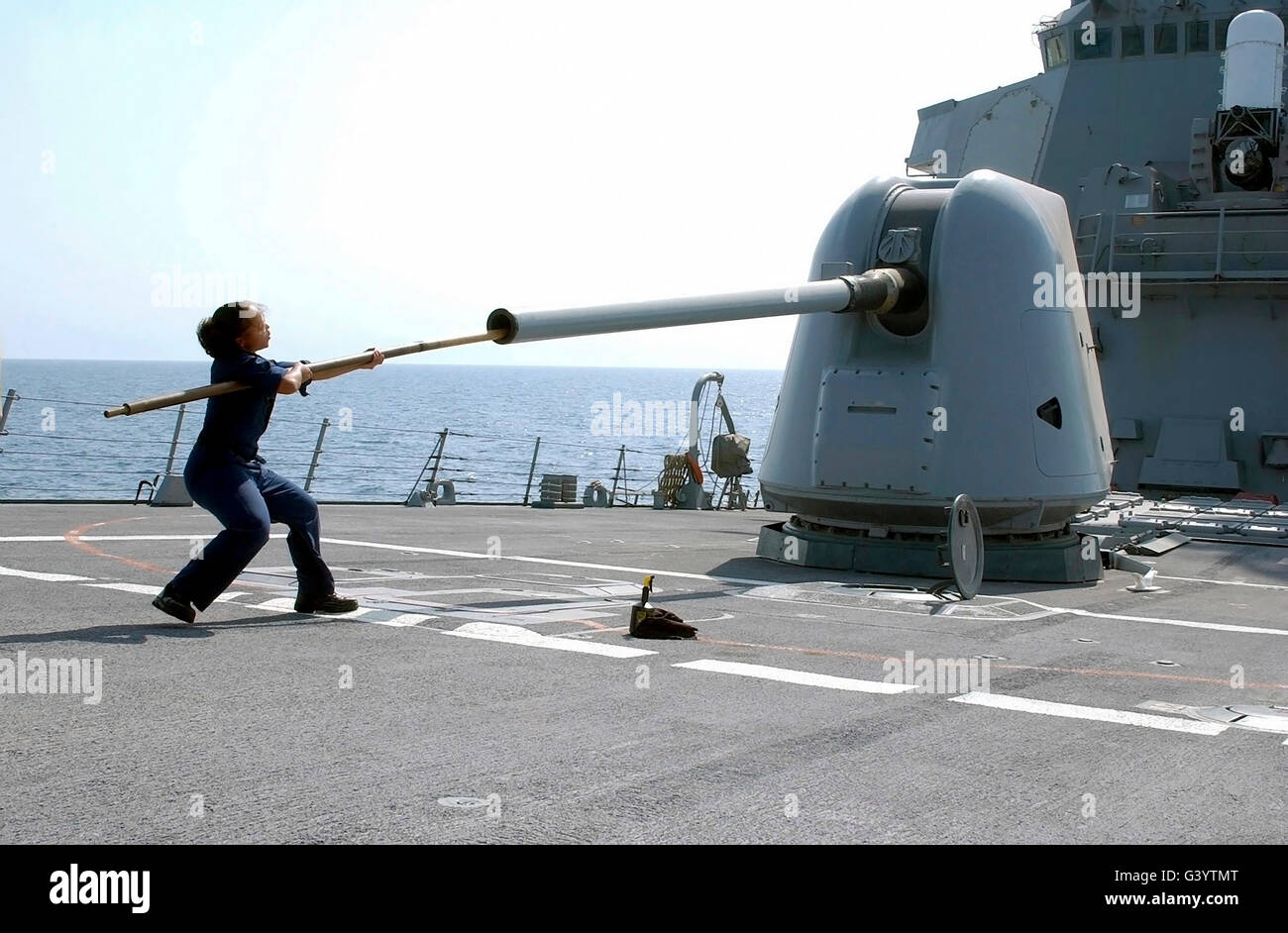Ein "Gunners" Mate reinigt den Lauf der Mark 45 auf dem Lenkflugkörper Zerstörer USS Trichter. Stockfoto