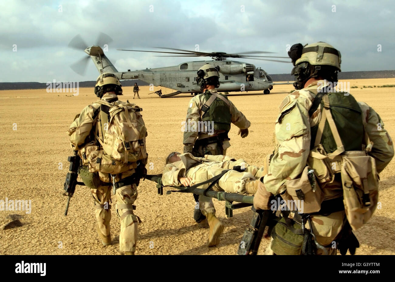 Ein Opfer wird von Pararescuemen in Richtung einer CH-53-Super-Hengst auf einer Bahre getragen. Stockfoto