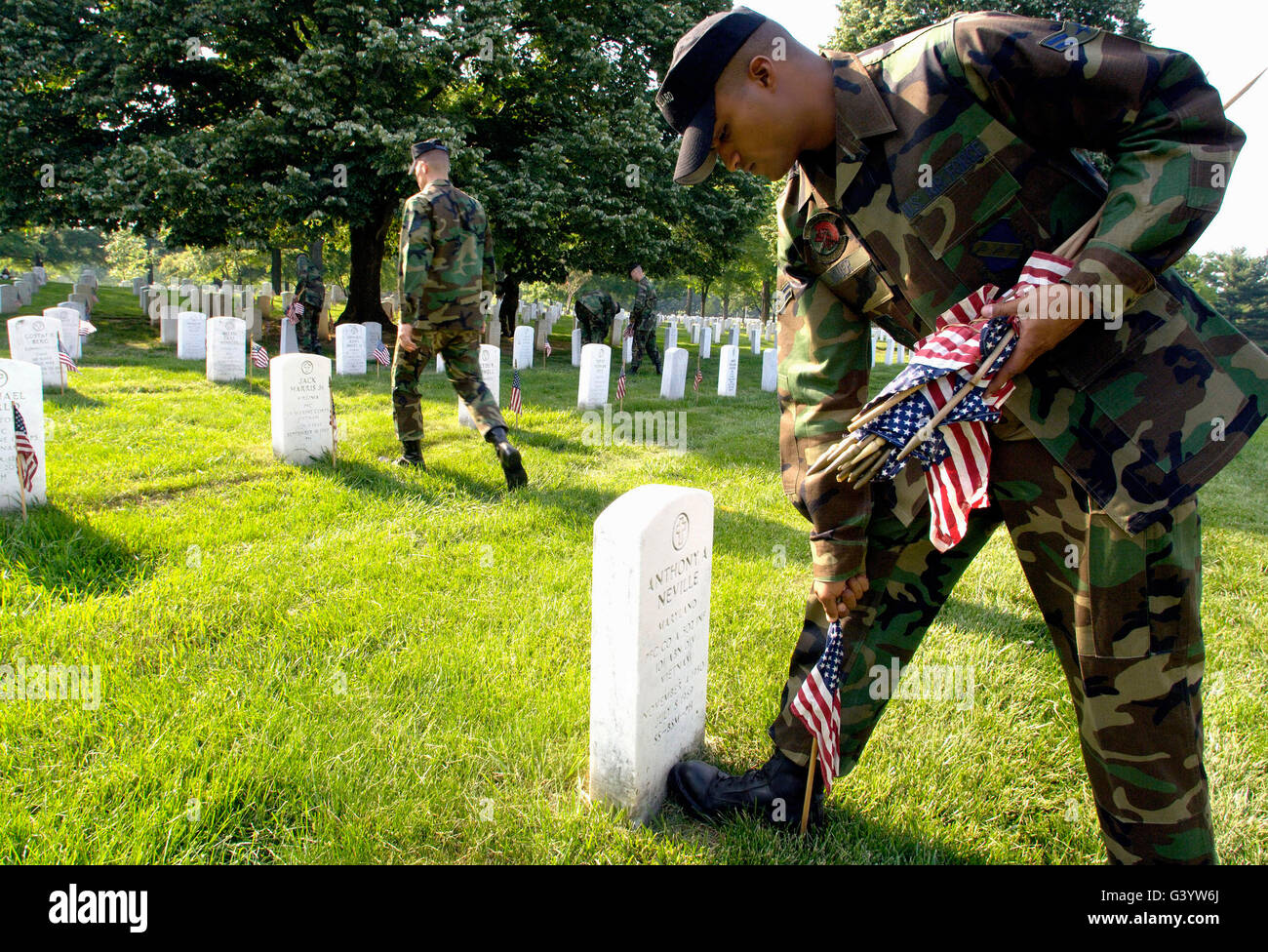 Ein Soldat stellt eine Flagge vor einem Grabstein. Stockfoto