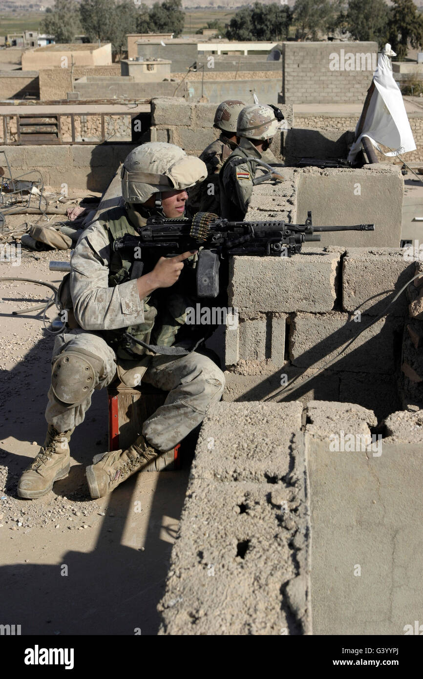 Ein US-Marine und Soldaten der irakischen Armee wacht über die umliegenden Straßen von einem Dach in Karabilah, Irak. Stockfoto