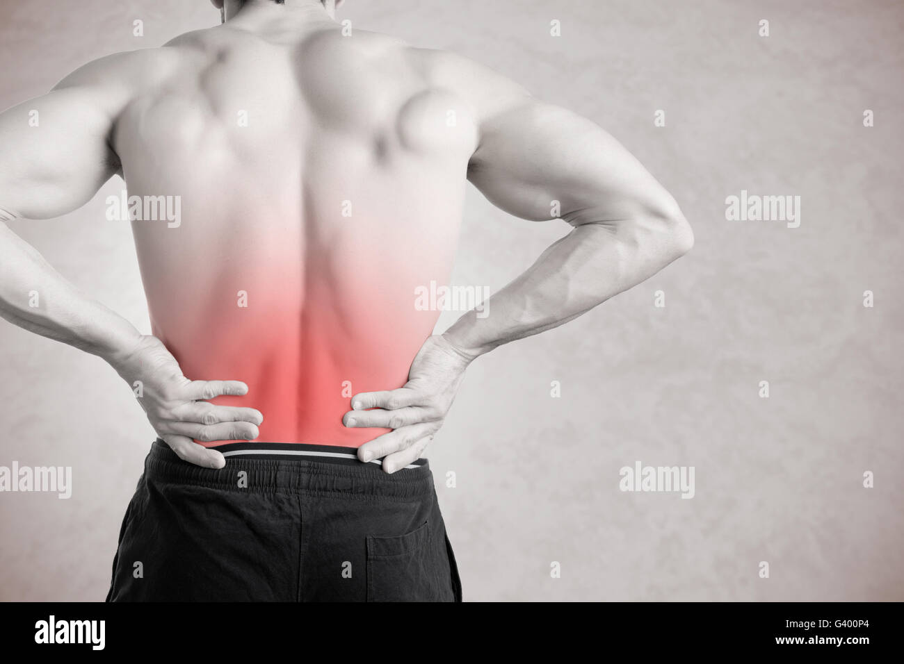 Sportler mit Schmerzen im unteren Rücken, isoliert in grau. Roter Fleck um die schmerzende Stelle. Stockfoto