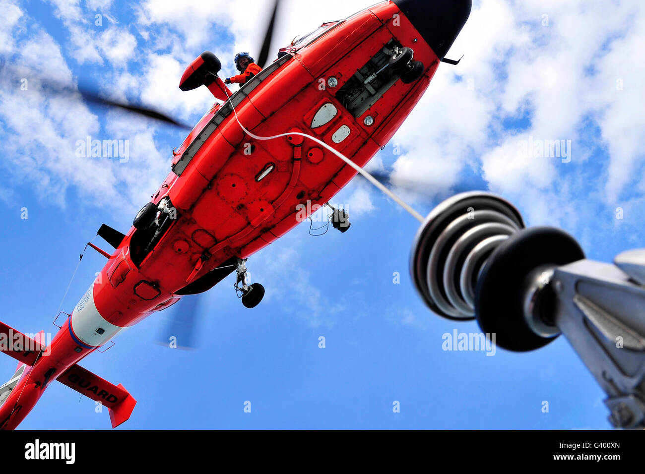 Chief Petty Officer sieht aus der Tür ein HH-65 Dolphin-Helikopter. Stockfoto