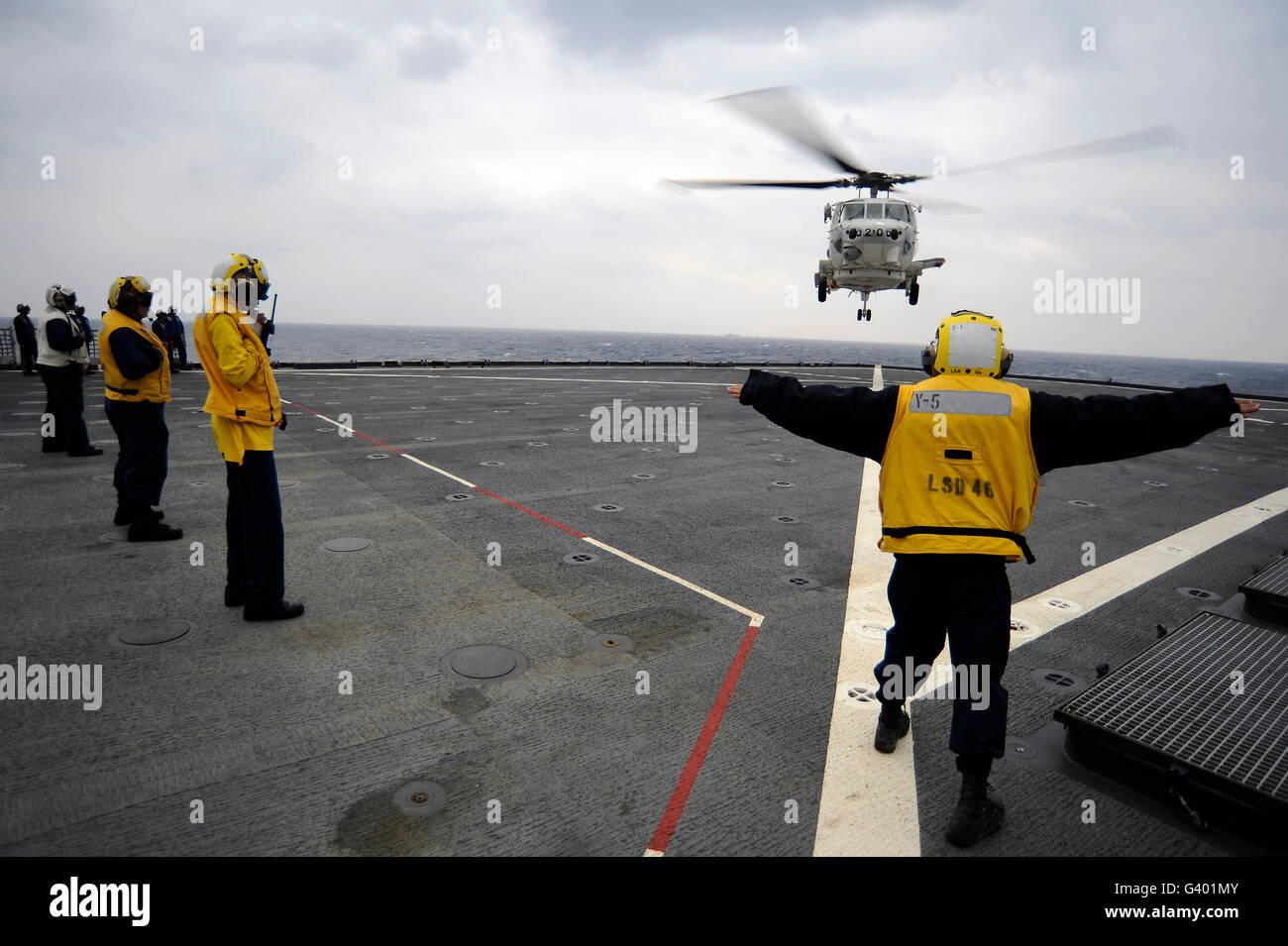 US Marine Bootsmann Mate leitet einen H-60 Hubschrauber auf dem Flugdeck der USS Tortuga. Stockfoto