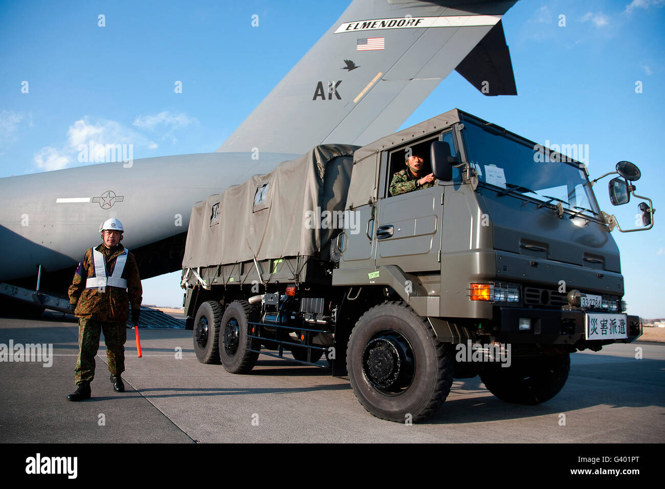 Ein japanischer Soldat Marschälle Fahrzeuge aus einer c-17 Globemaster III. Stockfoto