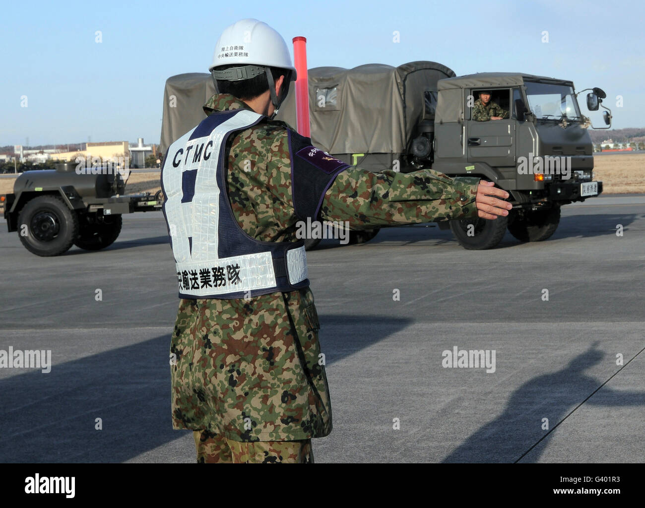 Ein japanischer Soldat Marschälle Fahrzeuge aus einer c-17 Globemaster III. Stockfoto