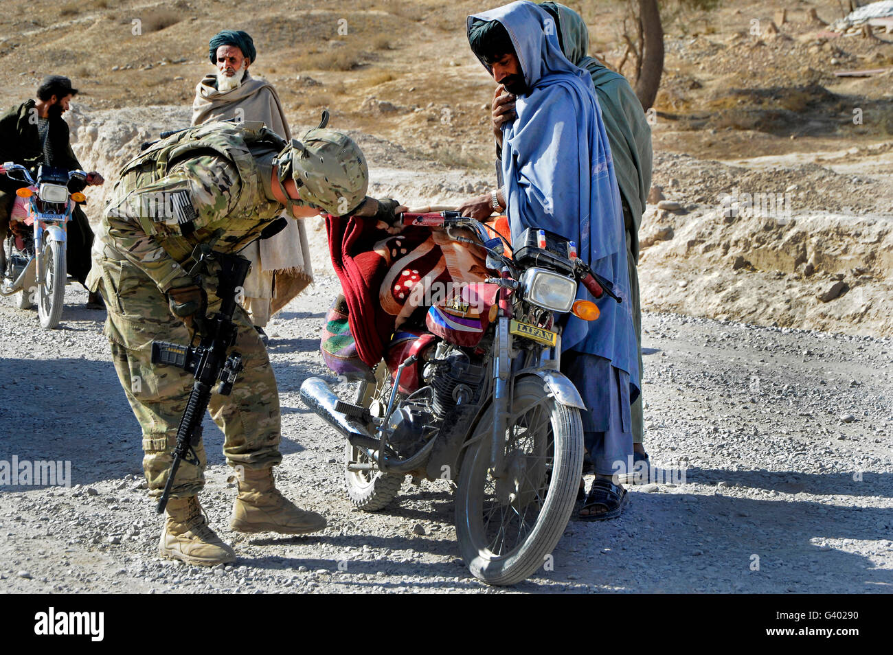 US Army Soldat führt Fahrzeug- und Personal sucht an einem Kontrollpunkt in Afghanistan. Stockfoto