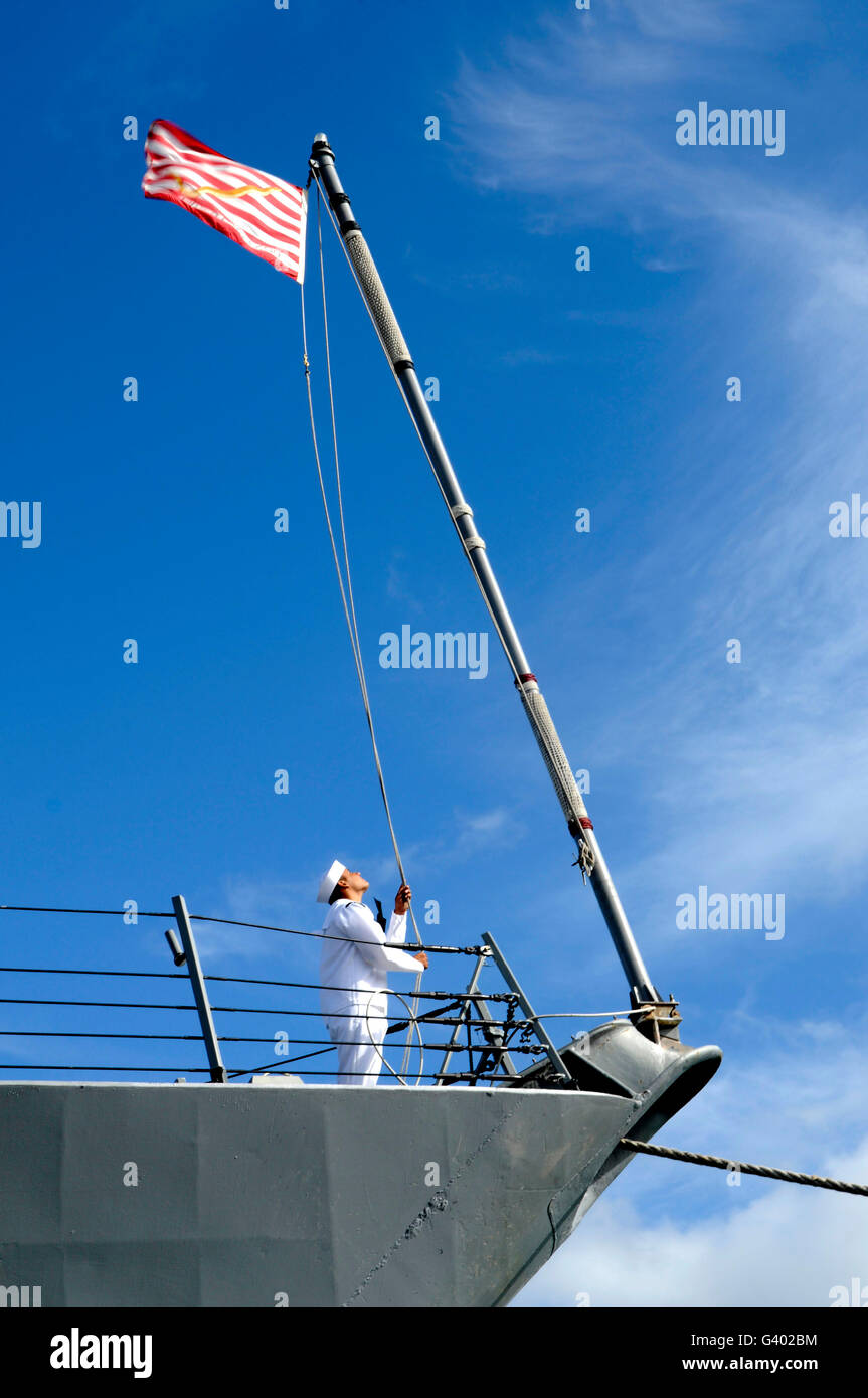 Ein Seemann senkt die US Navy Jack an Bord USS Chafee. Stockfoto