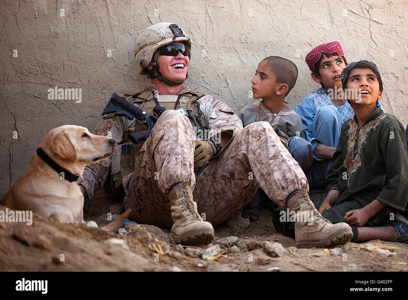 Ein US-Marine Witze mit afghanischen Kindern außerhalb einer lokalen Residenz. Stockfoto