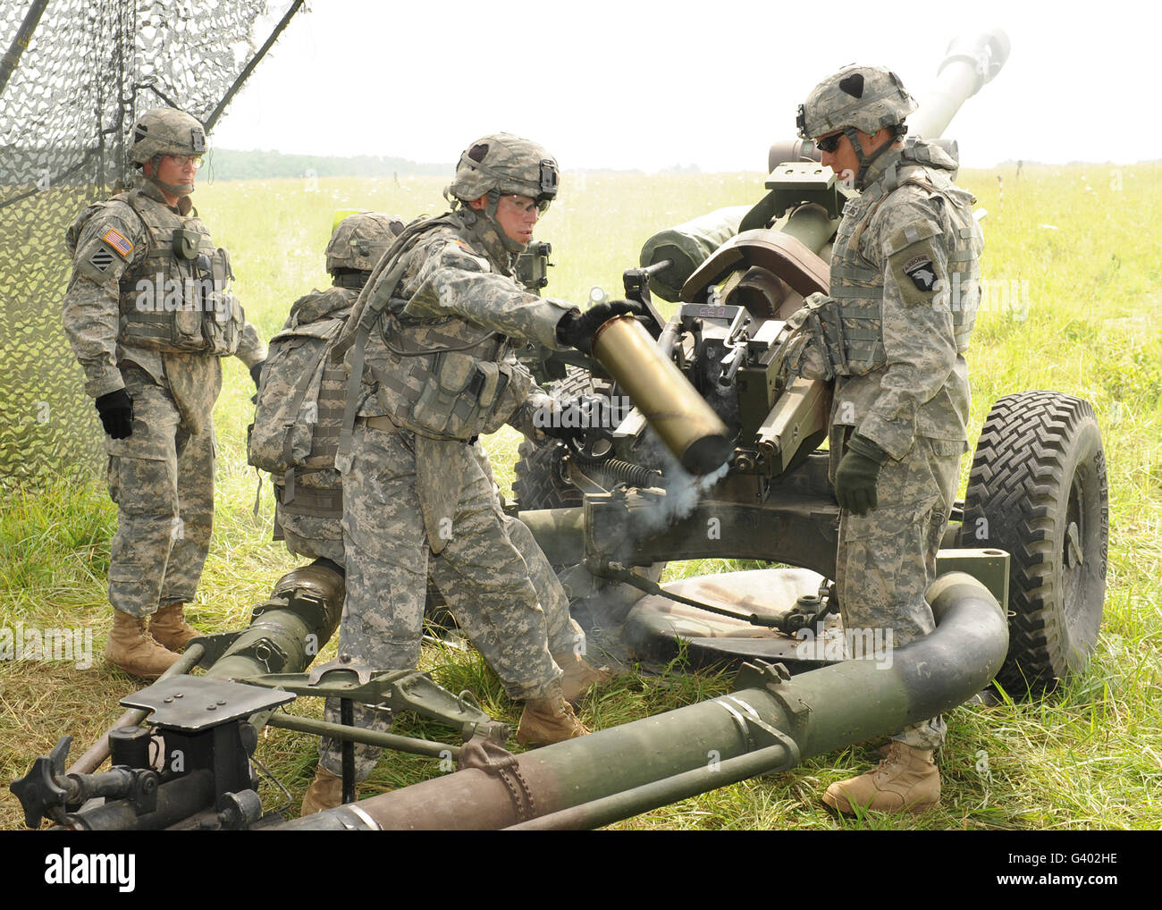 US Army Soldat wirft einen abgebrannten 105mm-Kanister aus einer Haubitze M119. Stockfoto