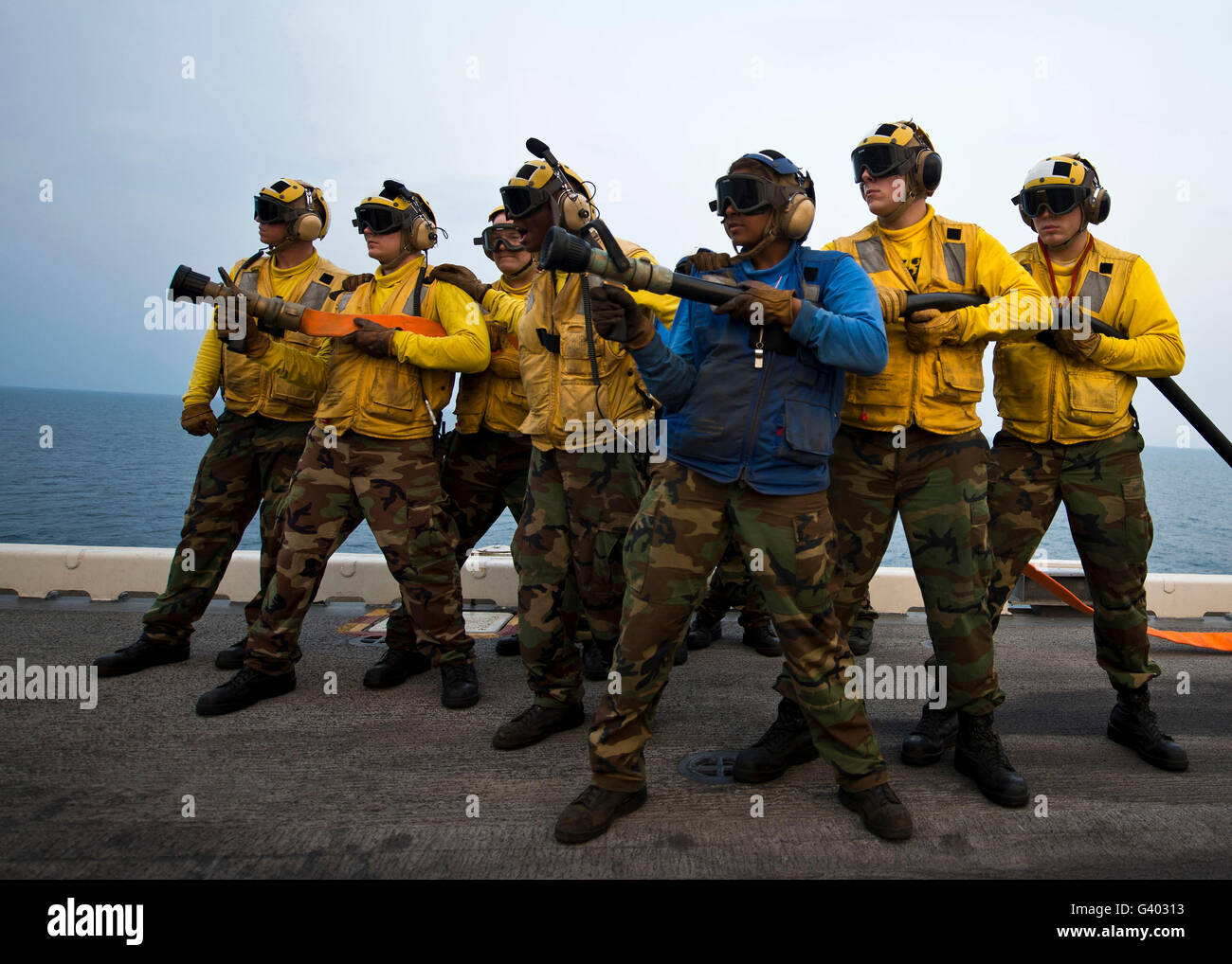 Feuer-Schlauch-Teams stehen im Falle von Reflash an Bord USS Bonhomme Richard. Stockfoto
