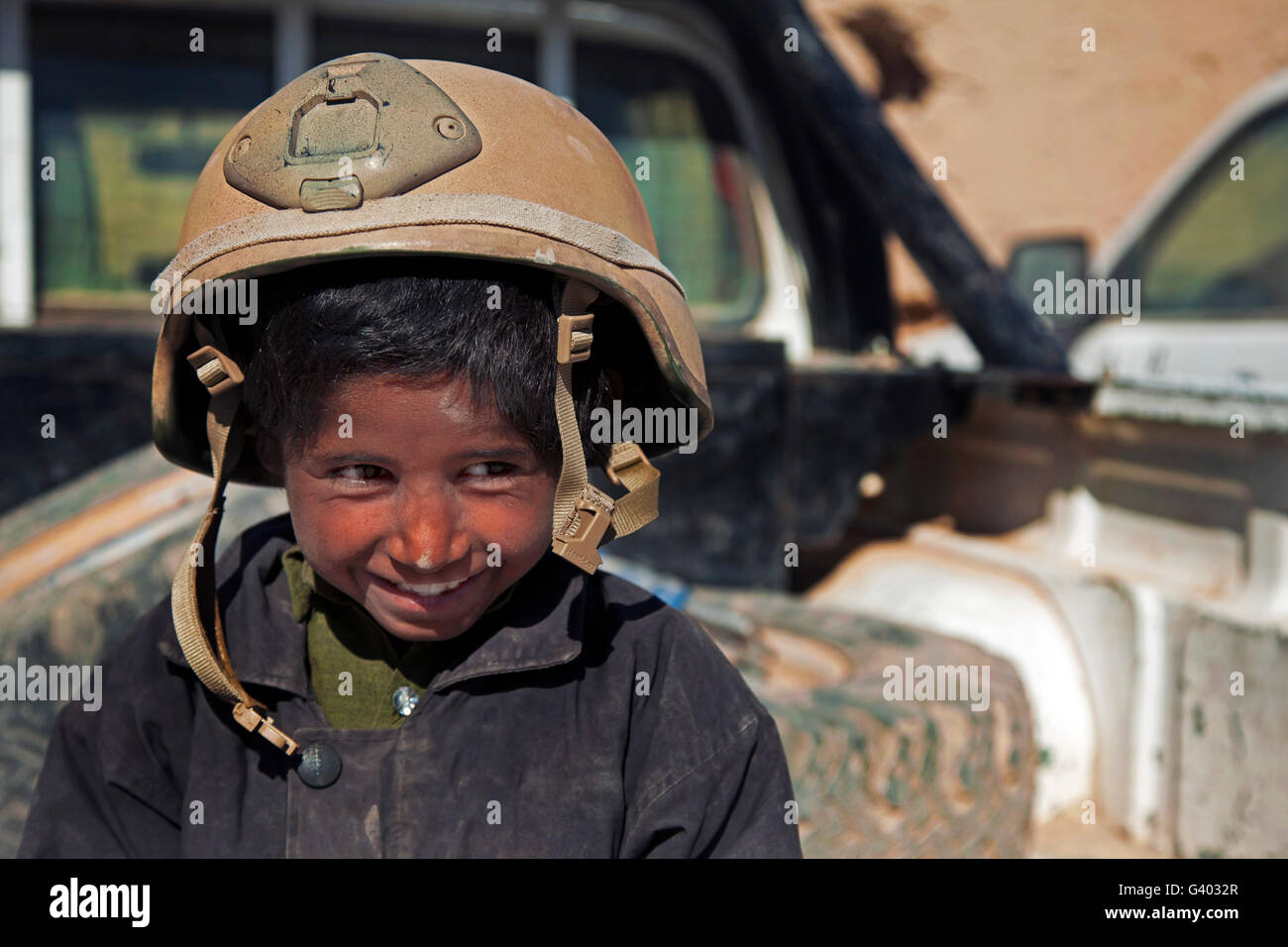 Ein kleiner Junge trägt eine Koalition Kraft Mitglied Helm in Afghanistan. Stockfoto