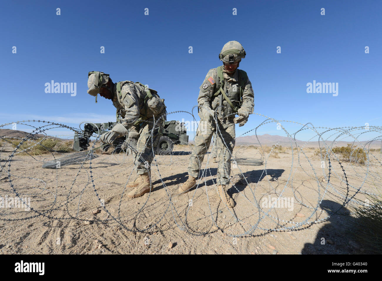 Soldaten wickeln Konzertina Draht an Fort Irwin, Kalifornien. Stockfoto