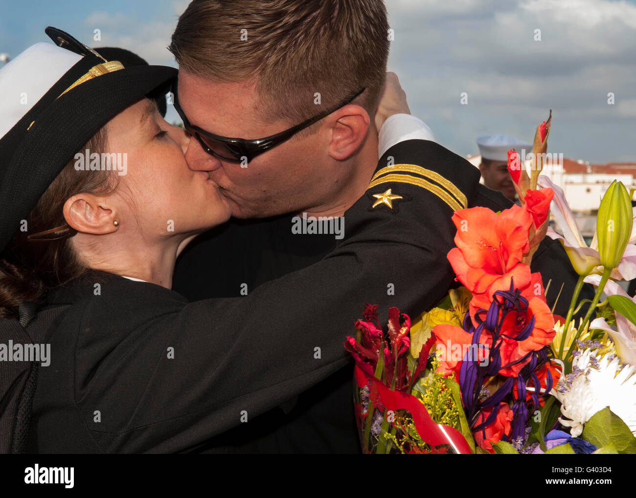 US Navy Lietutenant grüßt ihr Ehemann mit einem Kuss auf Heimkehr. Stockfoto