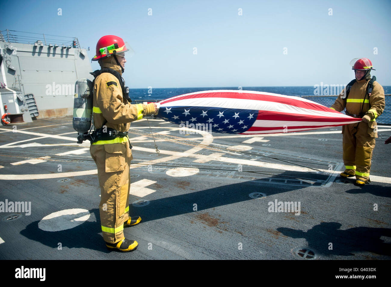 Feuerwehr Falten die amerikanische Flagge an Bord der USS William P. Lawrence. Stockfoto