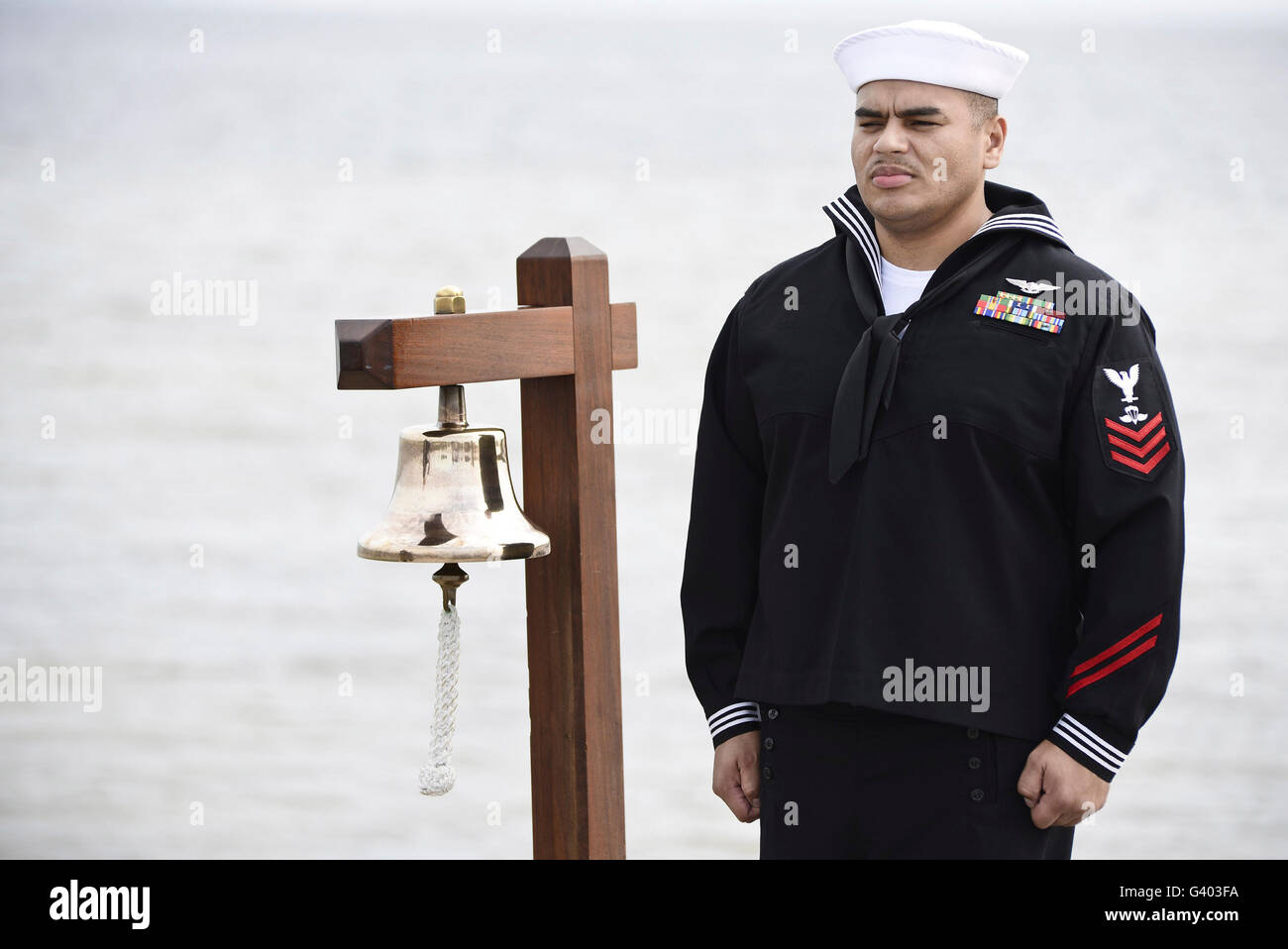 Seemann steht eine zeremonielle Glocke zu läuten. Stockfoto