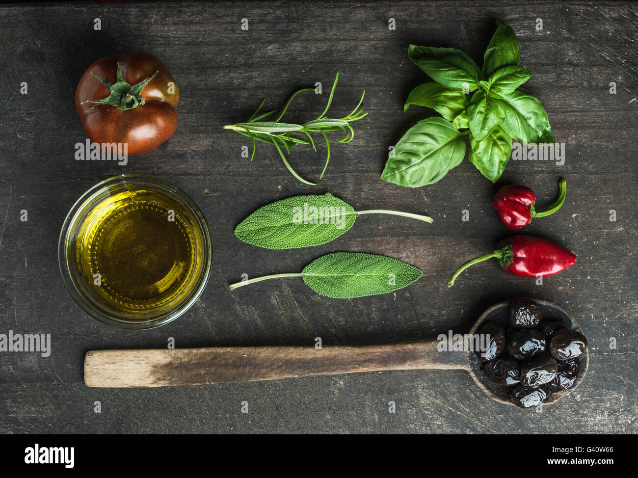 Gemüse und Kräuter auf dunklen rustikalen hölzernen Hintergrund. Griechische schwarze Oliven, frische grüne Salbei, Rosmarin, Basilikum-Kräuter, Öl, Tomaten, Stockfoto