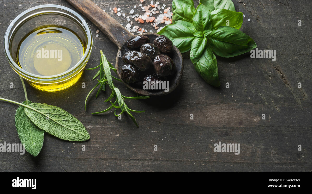 Griechische schwarze Oliven, frischer grüner Salbei, Rosmarin, Basilikum-Kräuter, Salz und Öl auf rustikalen Holz dunkel.  Ansicht von oben, Kopie spac Stockfoto