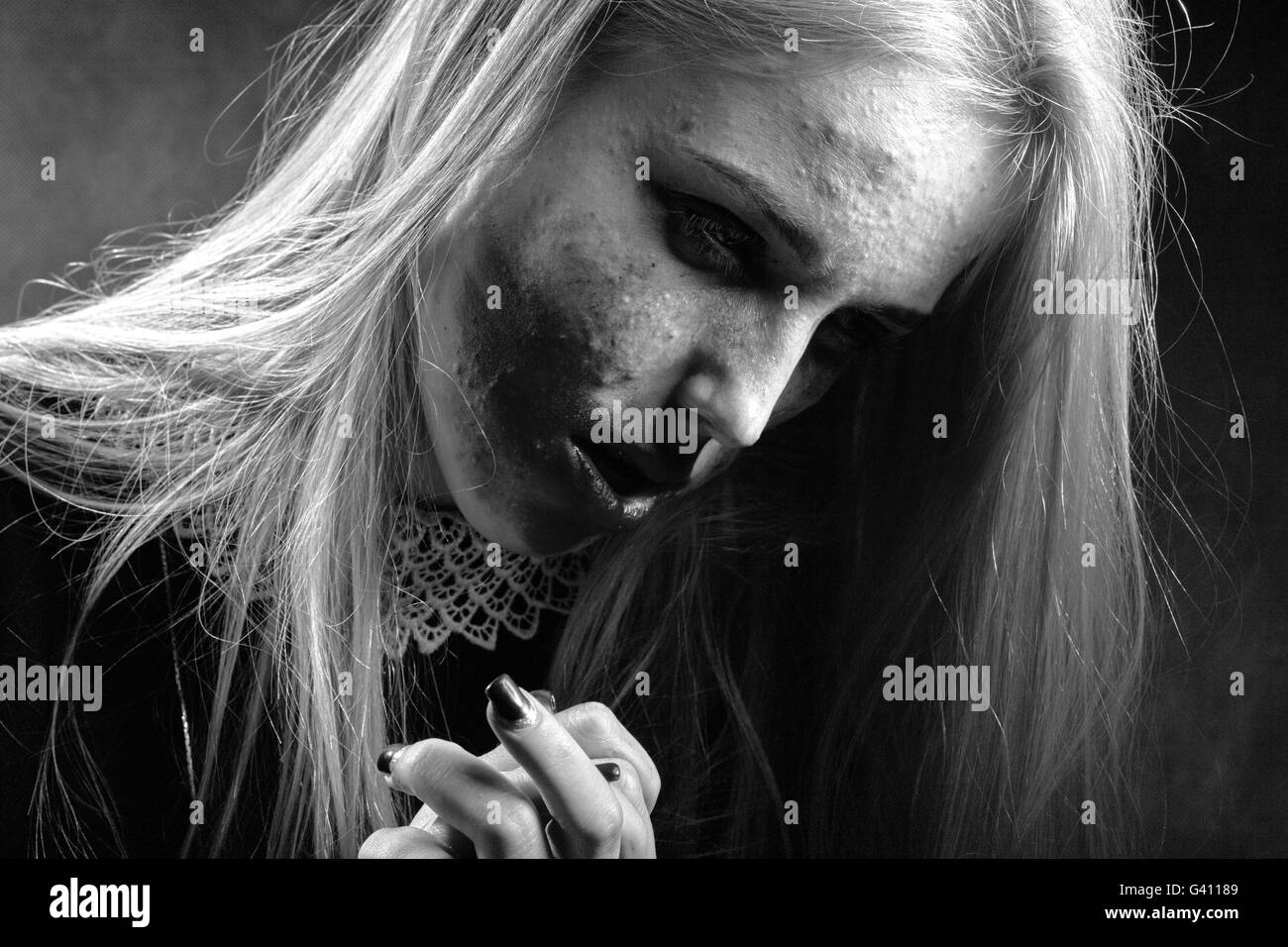 trauriges nachdenklich Mädchen mit verschmierten Kosmetik auf finnigen Haut auf schwarzem Hintergrund, Monochrom Stockfoto