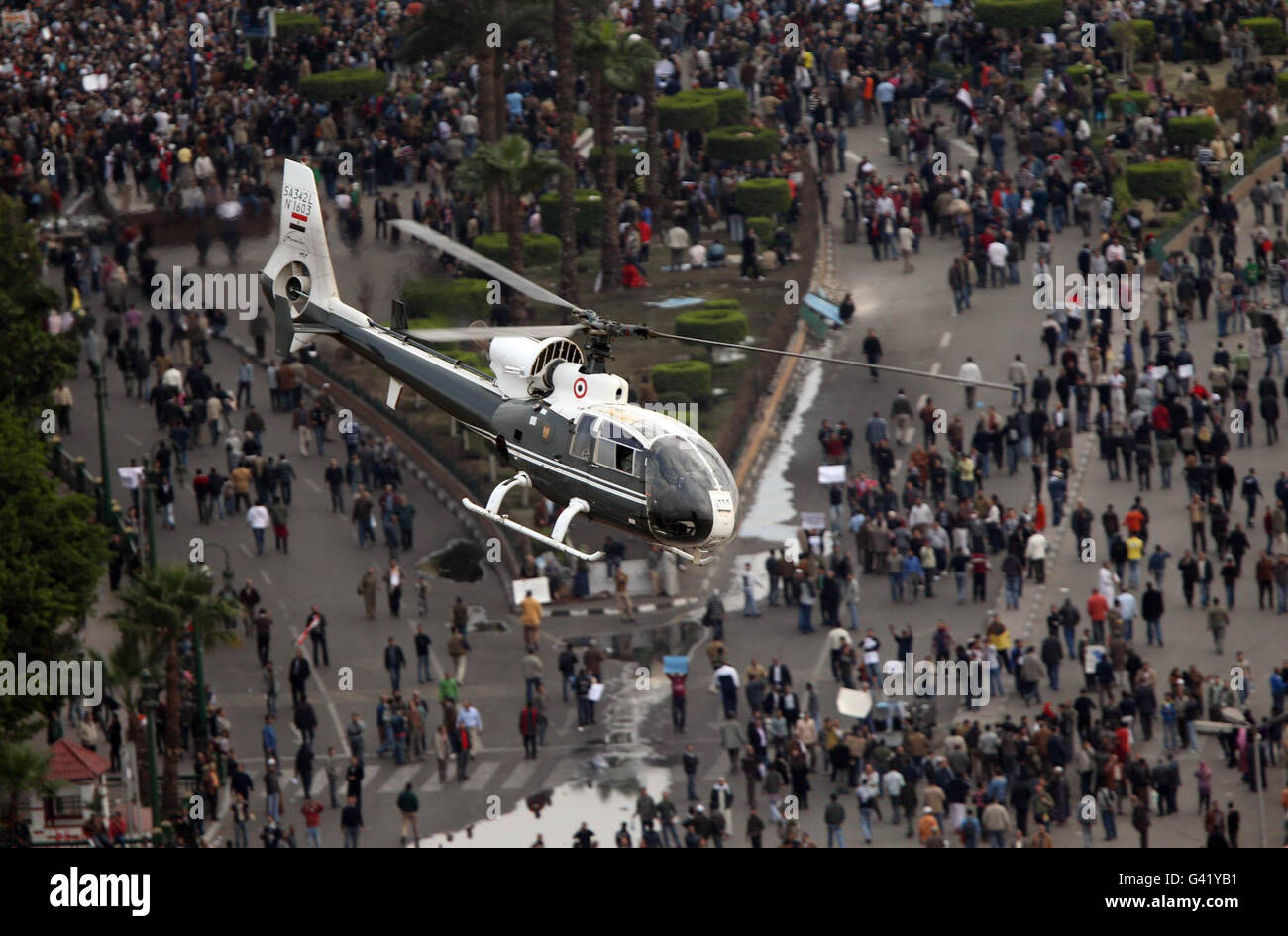 Ein Militärhubschrauber fliegt tief über den Tahrir-Platz in Kairo, Ägypten, während die Massenproteste gegen die drei Jahrzehnte währende Herrschaft von Präsident Hosni Mubarak im ganzen Land andauern. Stockfoto