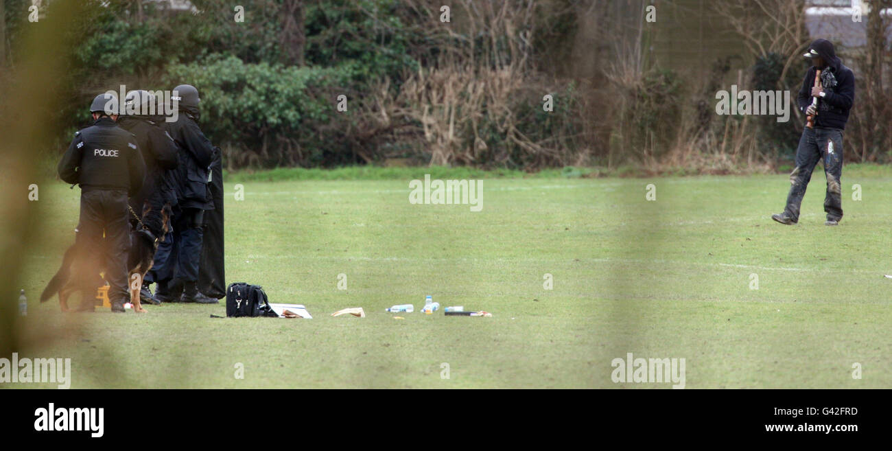 Ein Mann hält sich während eines Stands mit der bewaffneten Polizei im Leagrave Park im Zentrum von Luton, Bedfordshire, eine Waffe an den Kopf. Stockfoto