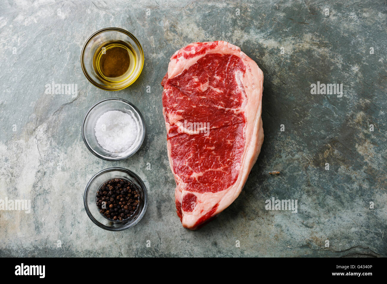 Rohes Frischfleisch Steak Roastbeef mit Speiseöl, Salz und Pfeffer auf Stein Schiefer Hintergrund Stockfoto