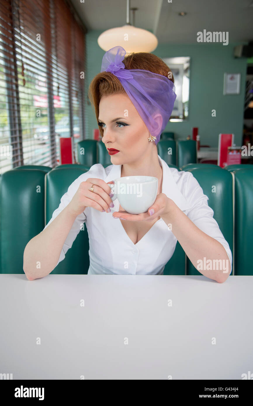 1960er Jahre schauen Pin-up Girl in einem American Diner hält eine Kaffeetasse Stockfoto