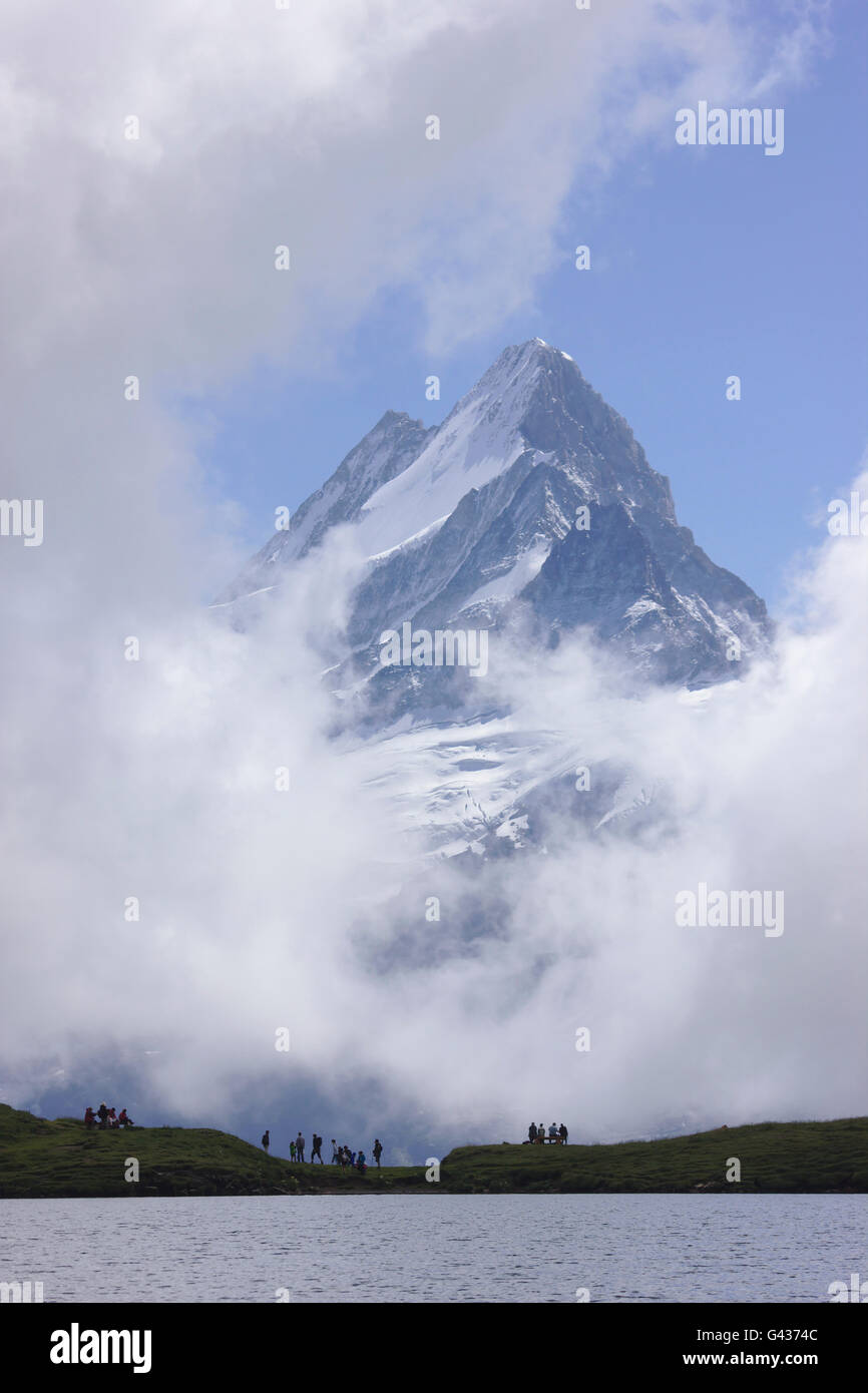 Schreckhorn eingerahmt von Wolken und Wanderer auf See Bachsee, in der Nähe von Grindelwald, Schweiz Stockfoto