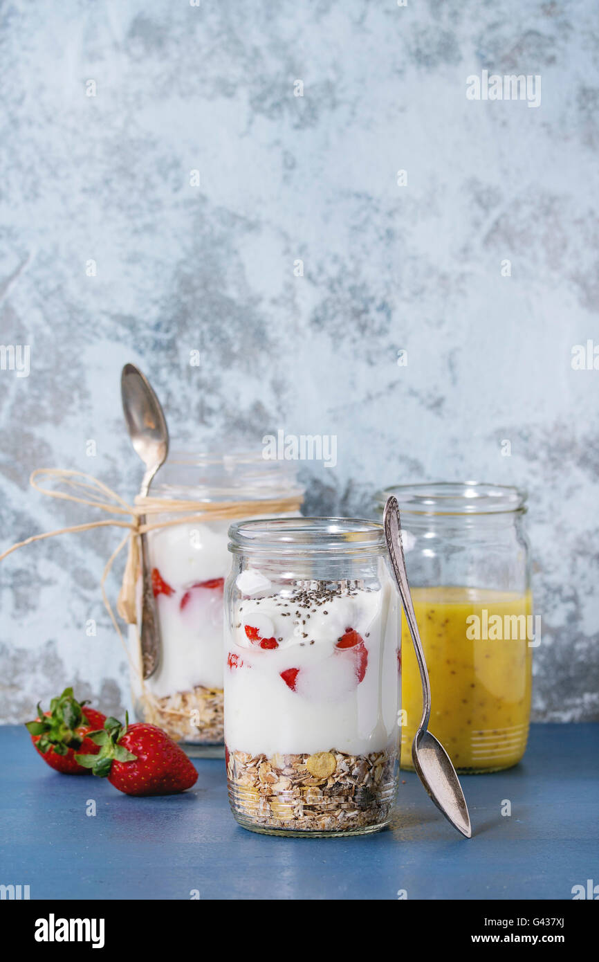 Gesundes Frühstück-Müsli, Erdbeeren und Joghurt mit Mango-Smoothie in Glas Einweckgläser. Serviert auf blauen Holztisch mit text Stockfoto