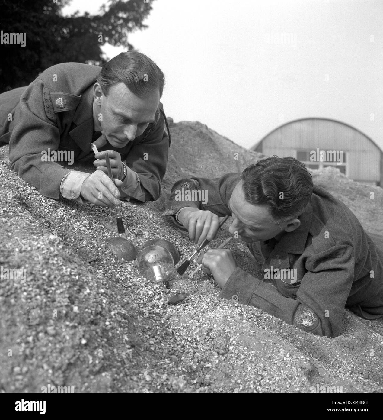 Major William Musson (links) und Warrant Officer I (Dirigent) Sidney Brazier, die mit der George Medal für Tapferkeit bei der Entsorgung von Bomben ausgezeichnet wurden, stellen die Umstände, die zu ihrer Auszeichnung führten, wieder her, da sie eine "ticky-Bombe" entwaffnen. Stockfoto