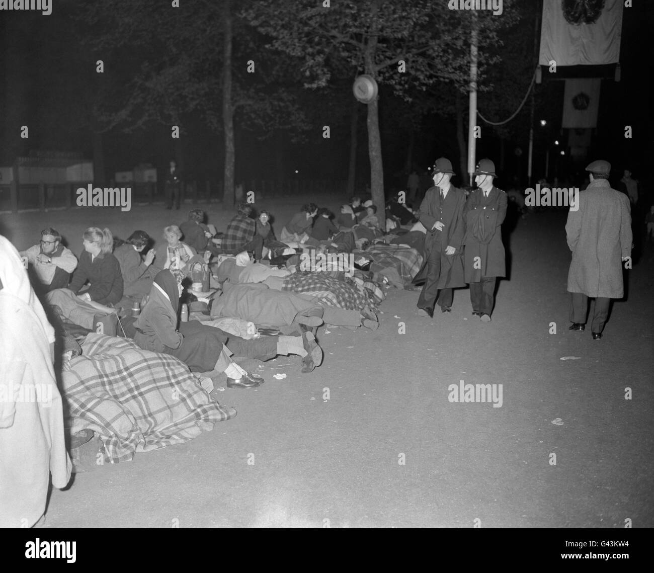 Patrouillierende Polizisten passieren schlafende Menschenmengen, die eine Nachtwache in der Mall hielten, um auf die Hochzeit von Prinzessin Margaret und Antony Armstrong-Jones vorbereitet zu sein Stockfoto