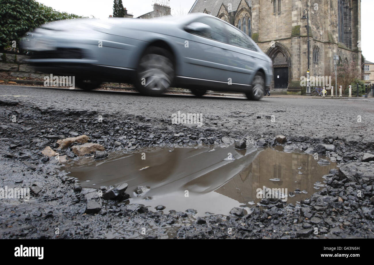 Schlaglöcher in Schottland. Ein Auto fährt an einem Schlagloch auf der University Avenue in Glasgow, Schottland vorbei. Stockfoto