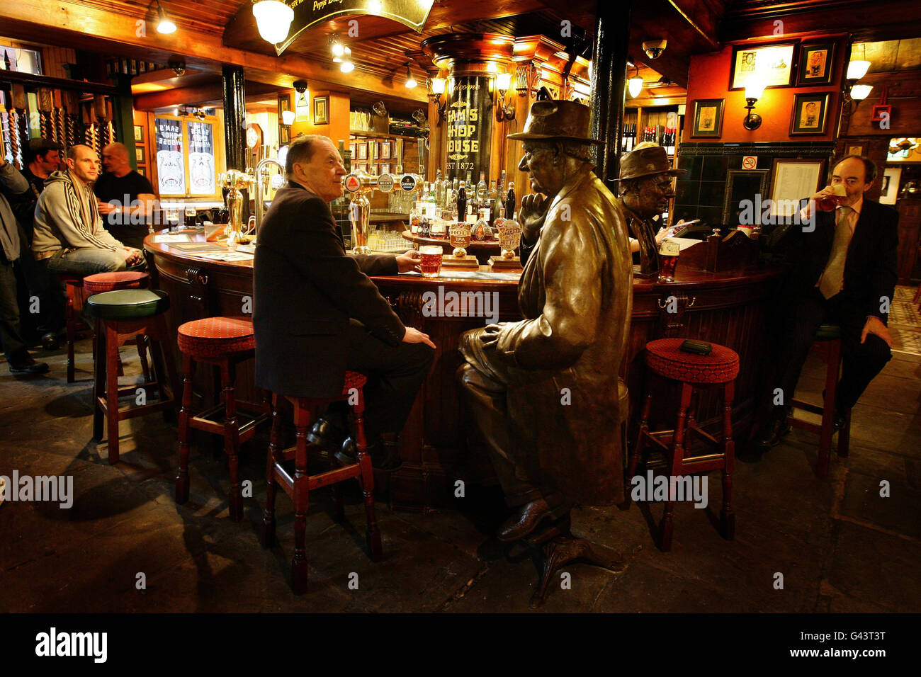 Ian Sandiford, ein alter Freund von L. S. Lowry sitzt und sieht eine lebensgroße Bronzestatue des Künstlers, nachdem sie in Sam's Chop House Pub in Manchester installiert wurde. Stockfoto